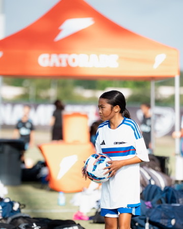 Soccer player holding a ball beside the Gatorade tent